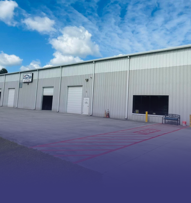 Warehouse with a metal facade and multiple loading doors, under a partly cloudy sky.