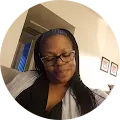 A woman wearing glasses is sitting in a room in a circle.