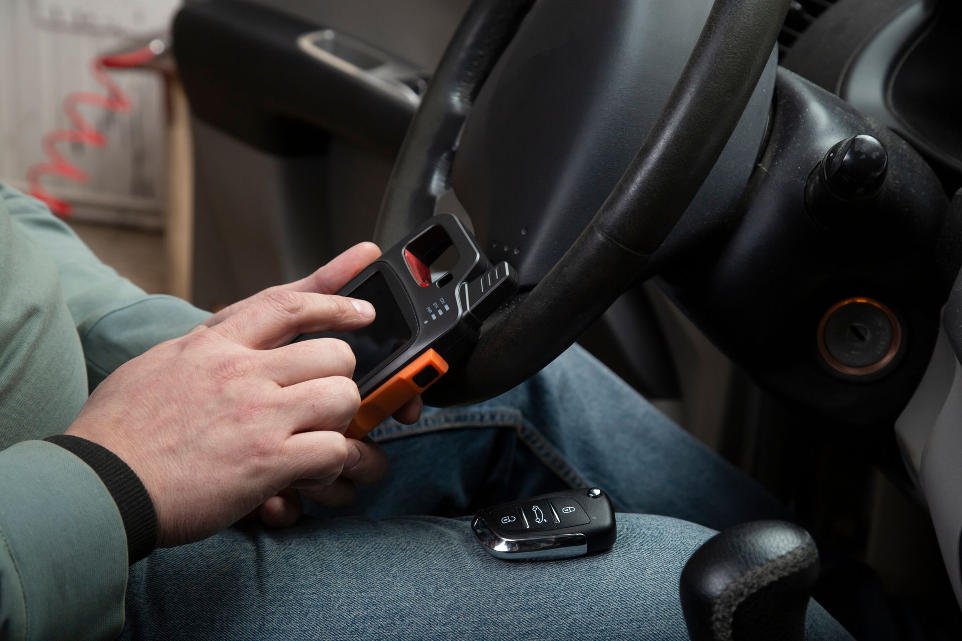 Hand gripping a car steering wheel while another hand uses a seat belt buckle