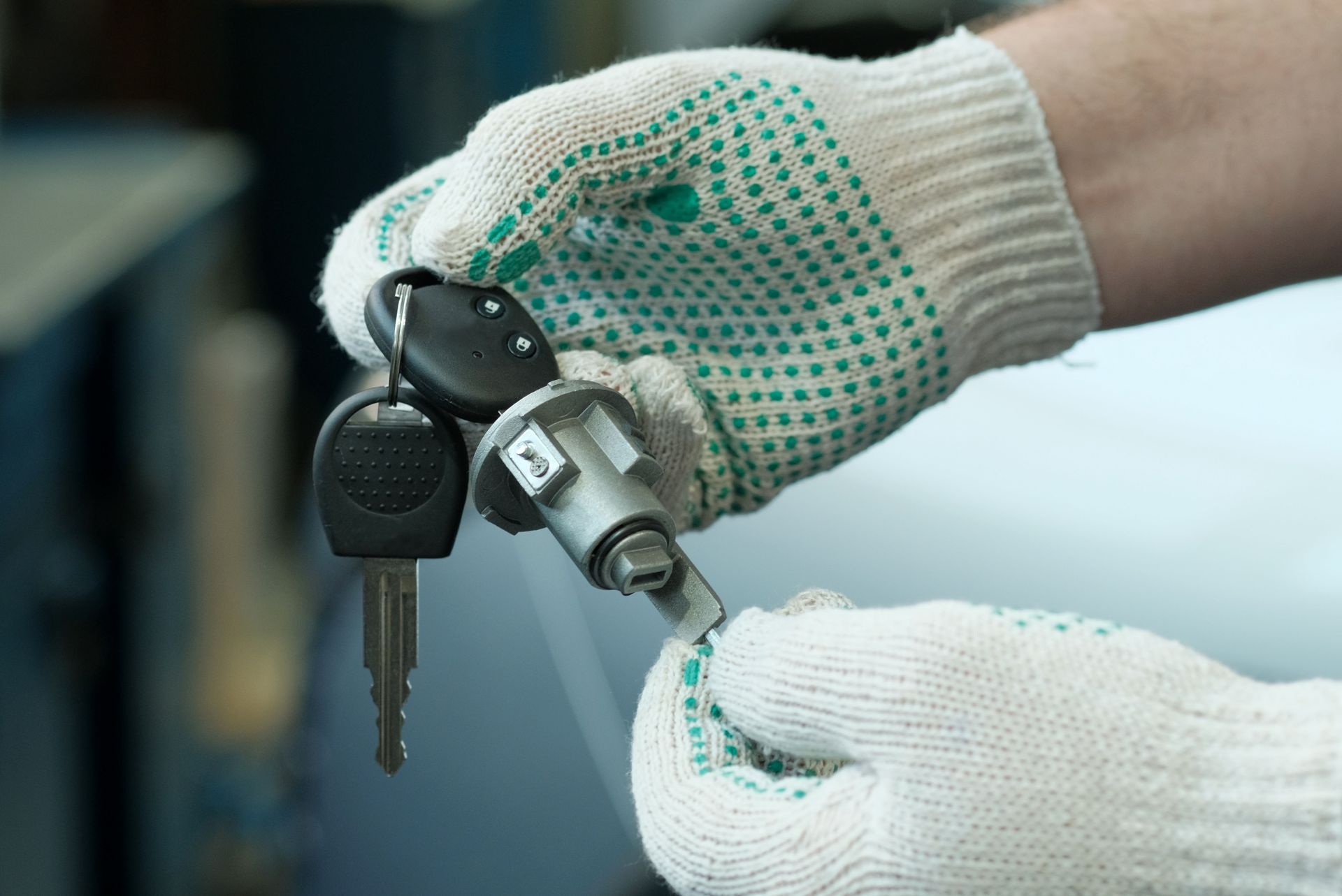Gloved hands holding a car key and key fob, inserting the key into a lock cylinder