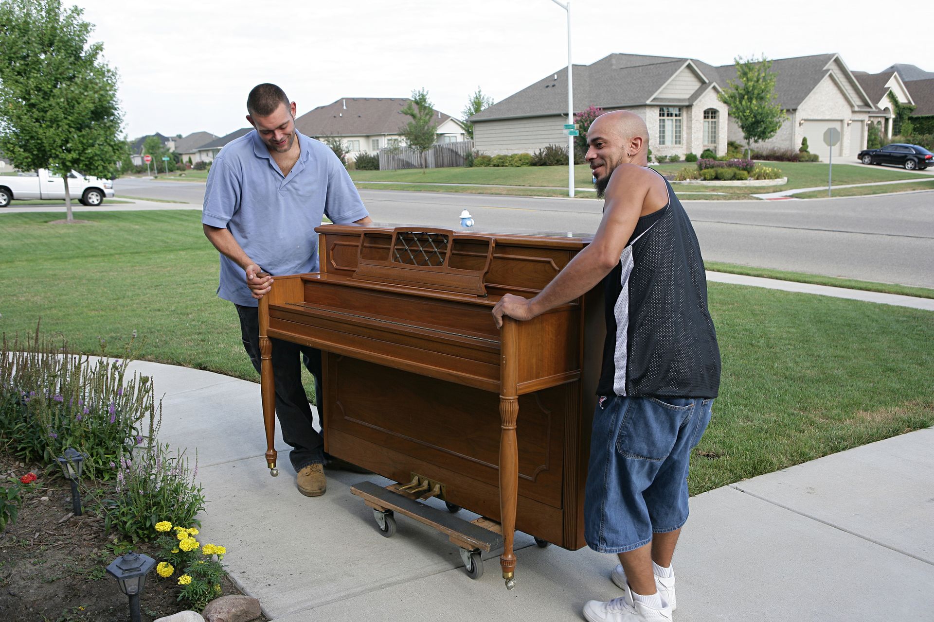 Two men moving a piano carefully down stairs, showcasing carefully piano moving techniques and teamwork in action