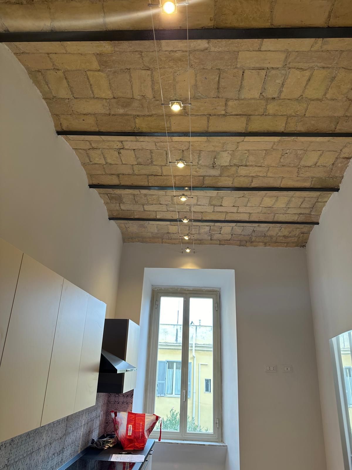 Soggiorno ristrutturato con soffitti originali e pavimenti moderni.