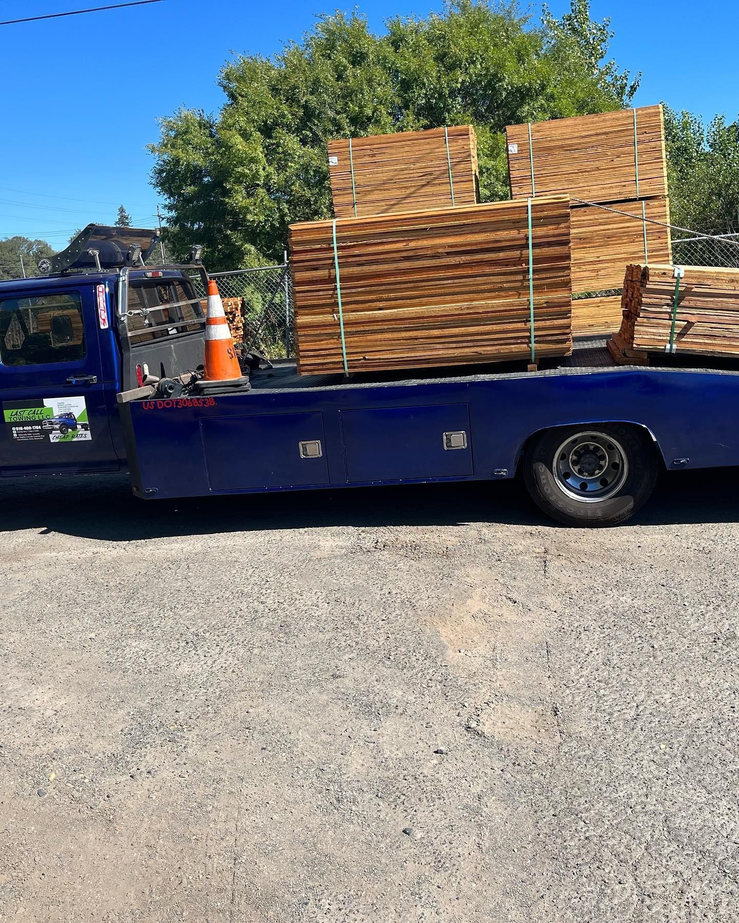 Blue flatbed truck loaded with stacked plywood sheets outdoors under a bright sky