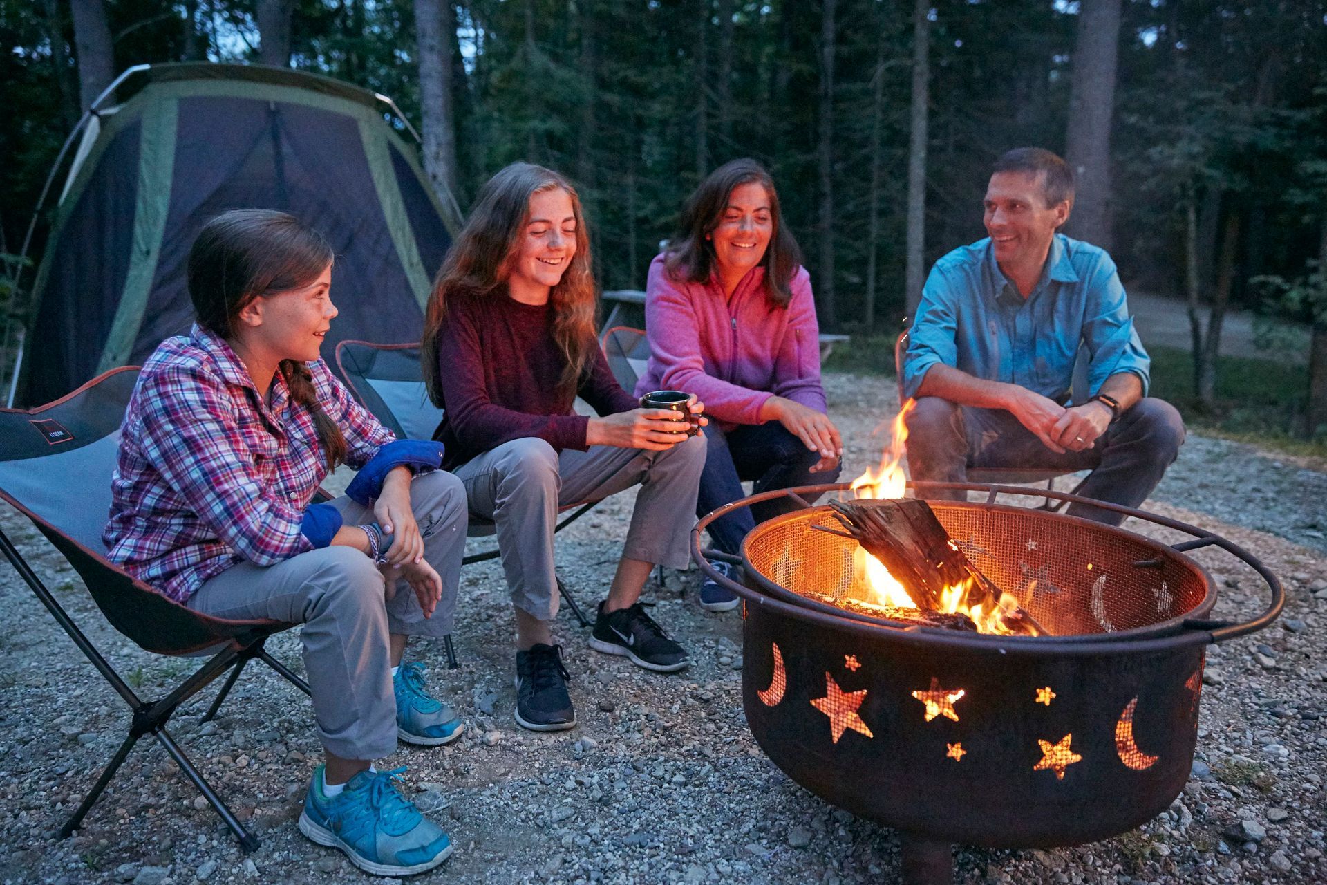 A family of four sitting around a fire pit