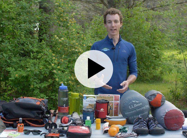 smiling man standing in front of a table full of hiking gear