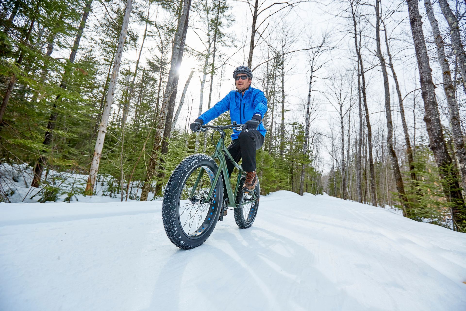 a man riding a fat tire bike on a groomed, snow covered trail.