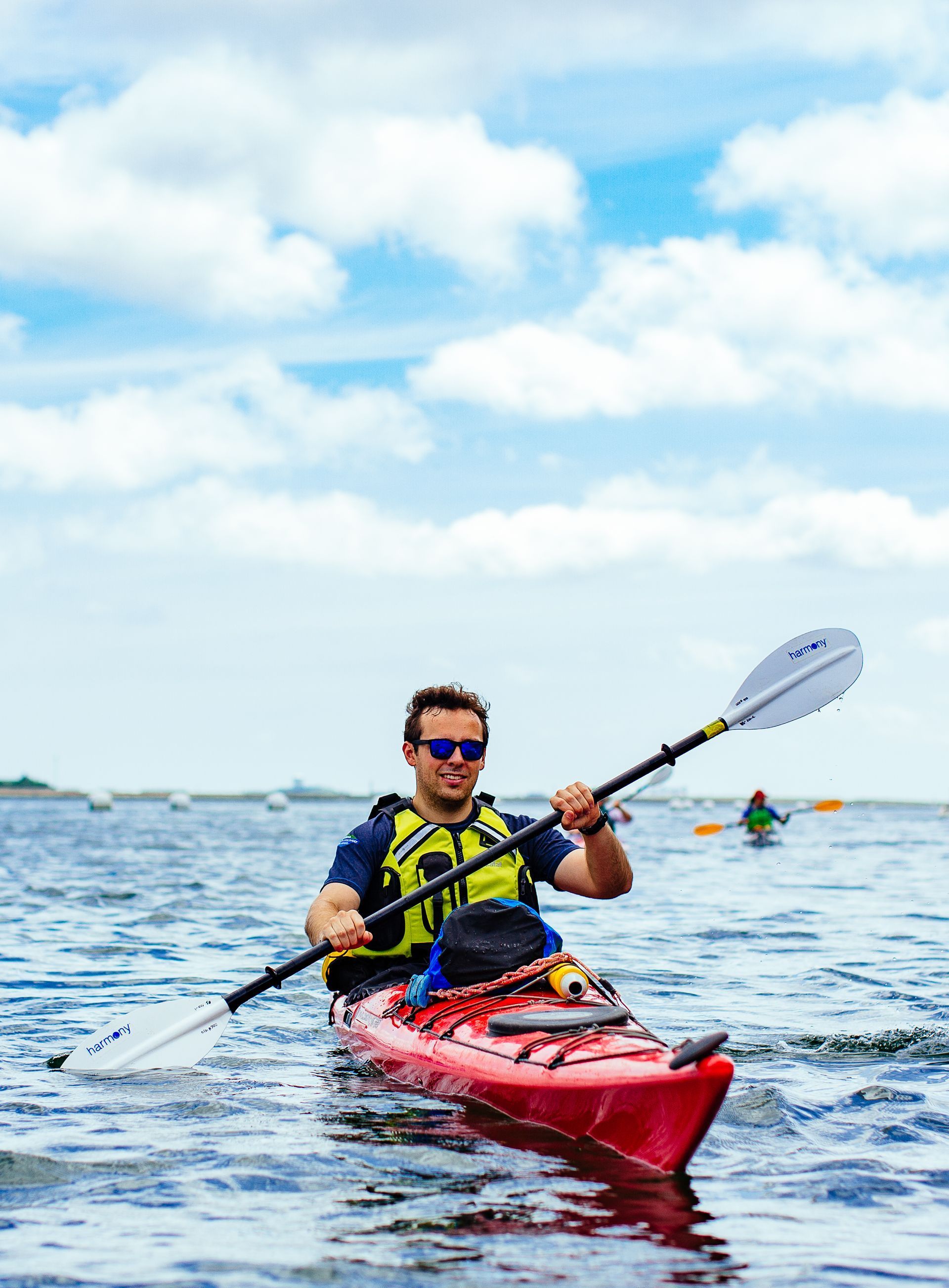 A man kayaking in Boston Harbor with several other kayakers in the background.