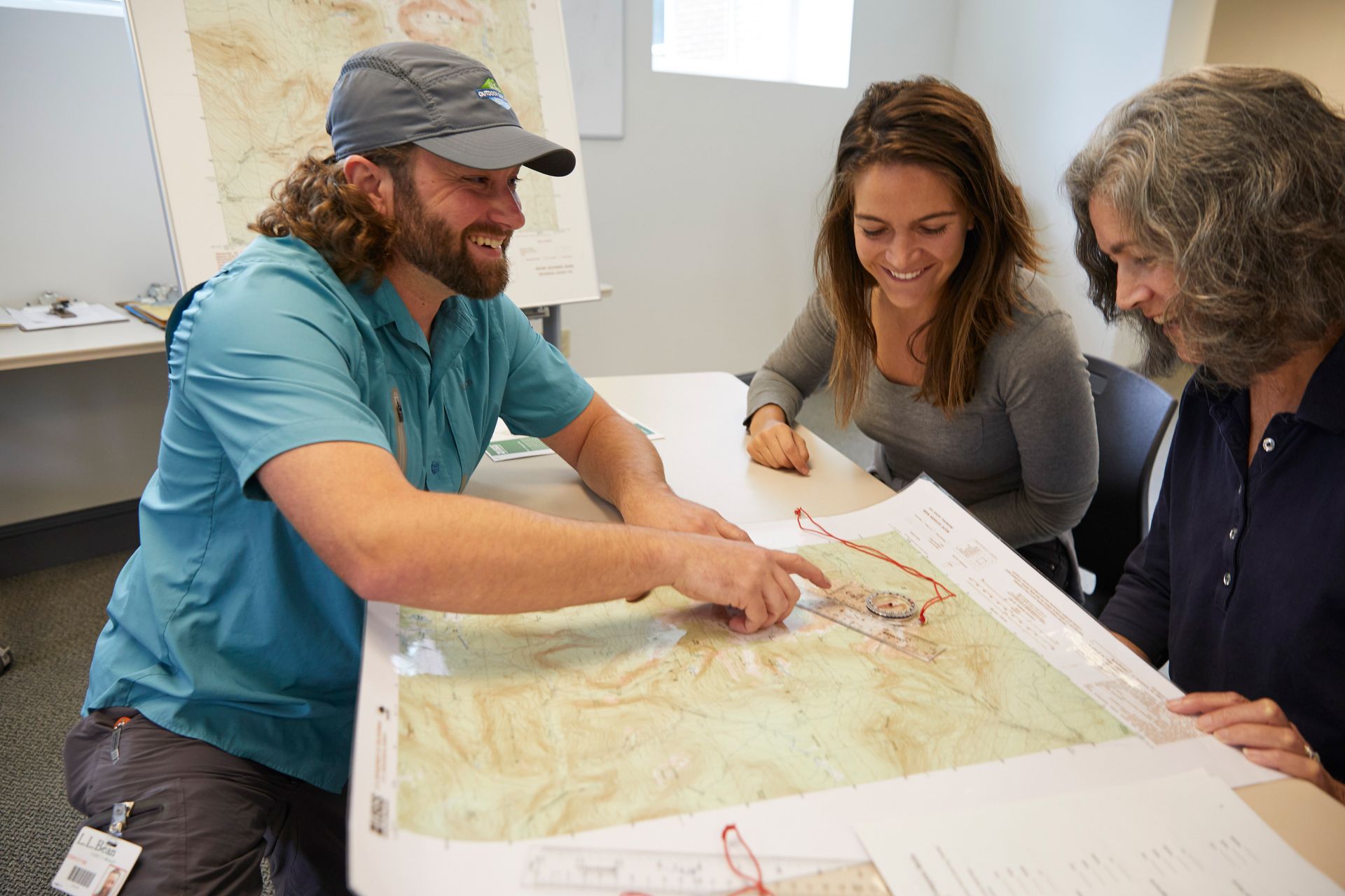 Instructor explaining how to find the direction of travel using a map and compass, to class participants.