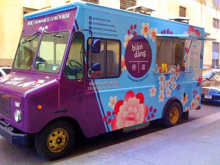 A purple and blue food truck is parked on the side of the road