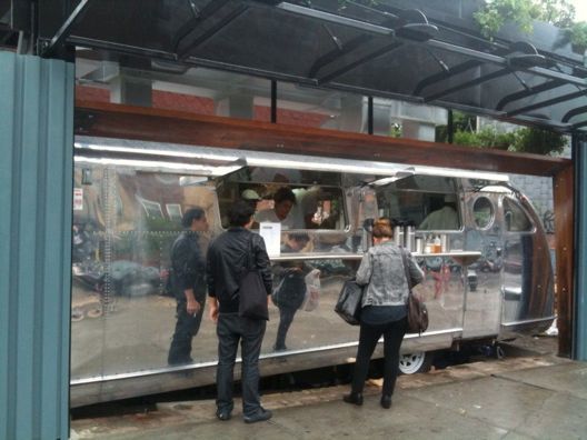 A group of people standing outside of a food truck