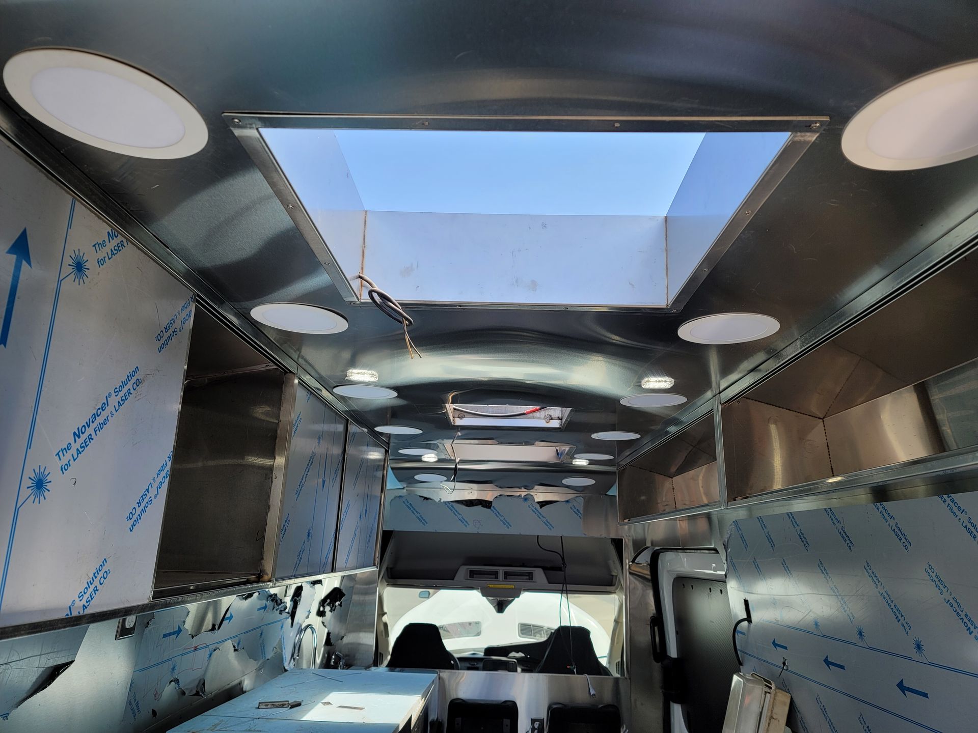 The inside of a stainless steel van with a skylight in the ceiling