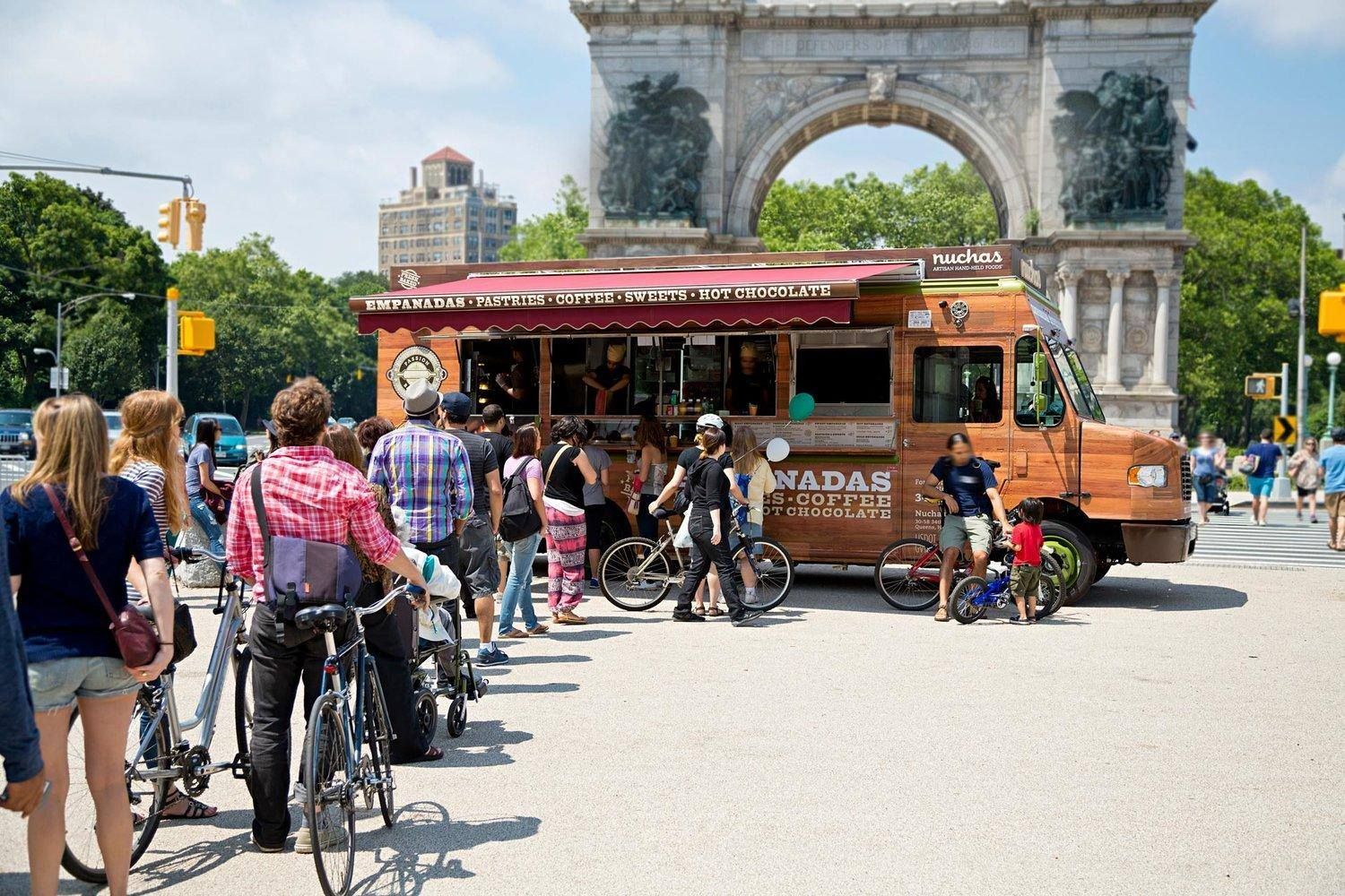 A group of people are standing in front of a food truck.