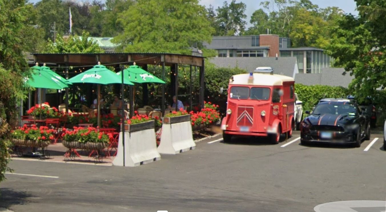 A red truck is parked in a parking lot next to a black car.