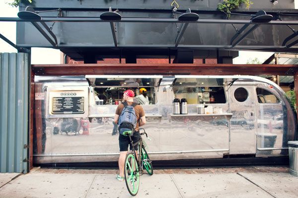 A man is riding a bike in front of a food truck.