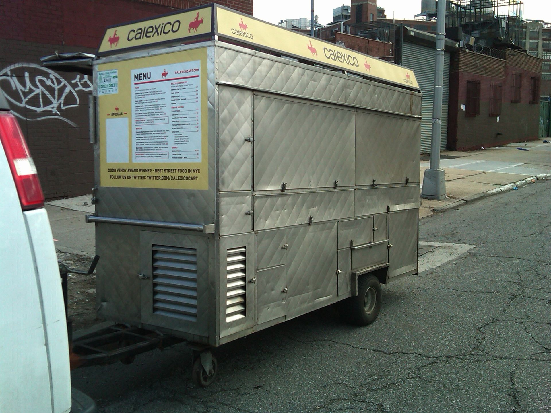 A stainless steel food cart with a menu on it