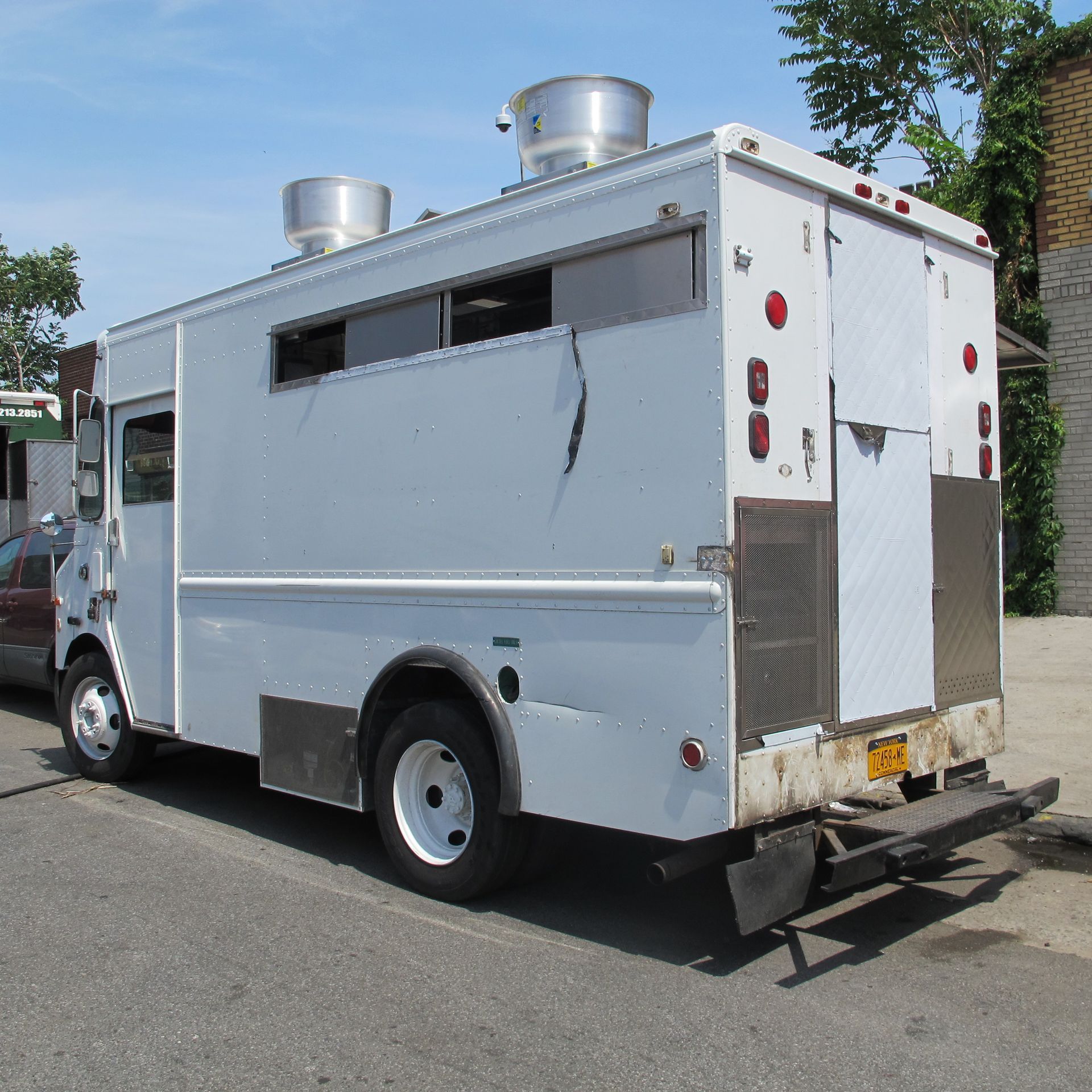 A white food truck is parked on the side of the road