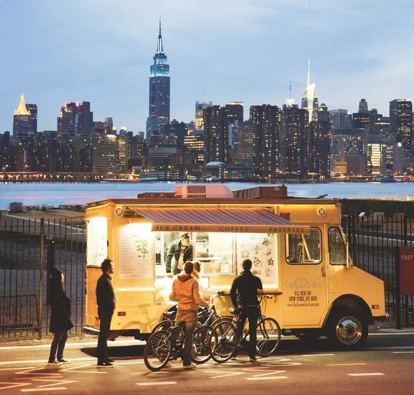 A food truck is parked in front of a city skyline