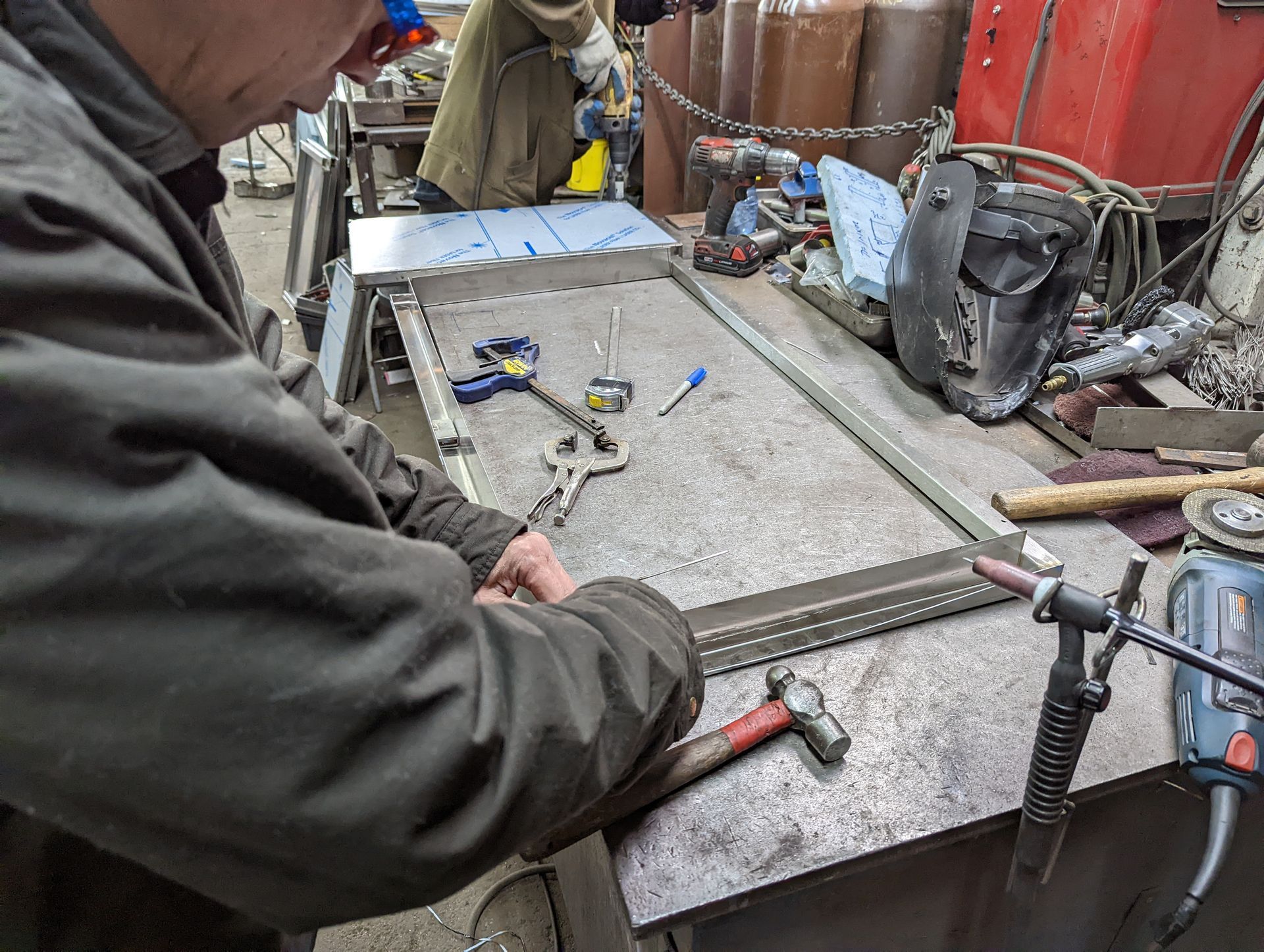 A man is working on a piece of metal on a table.