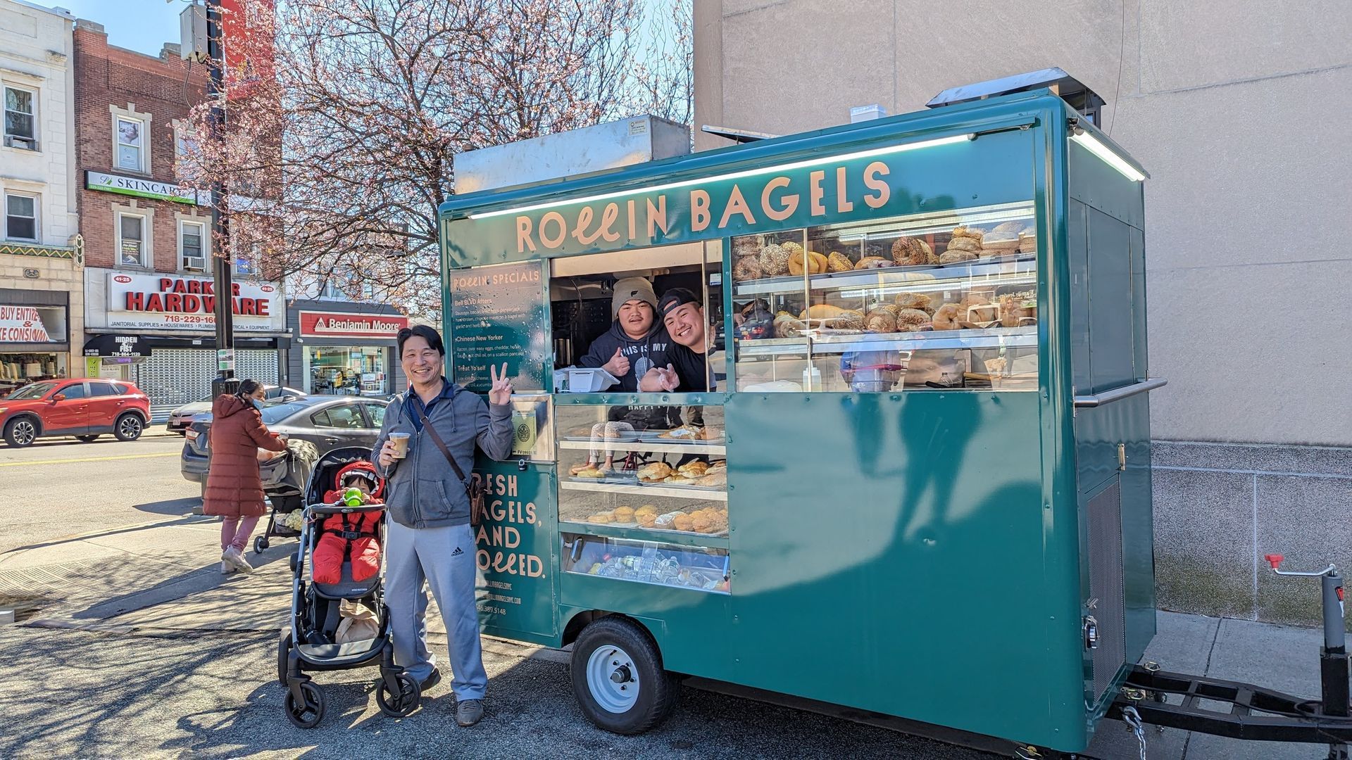 A man is standing in front of a green food truck.