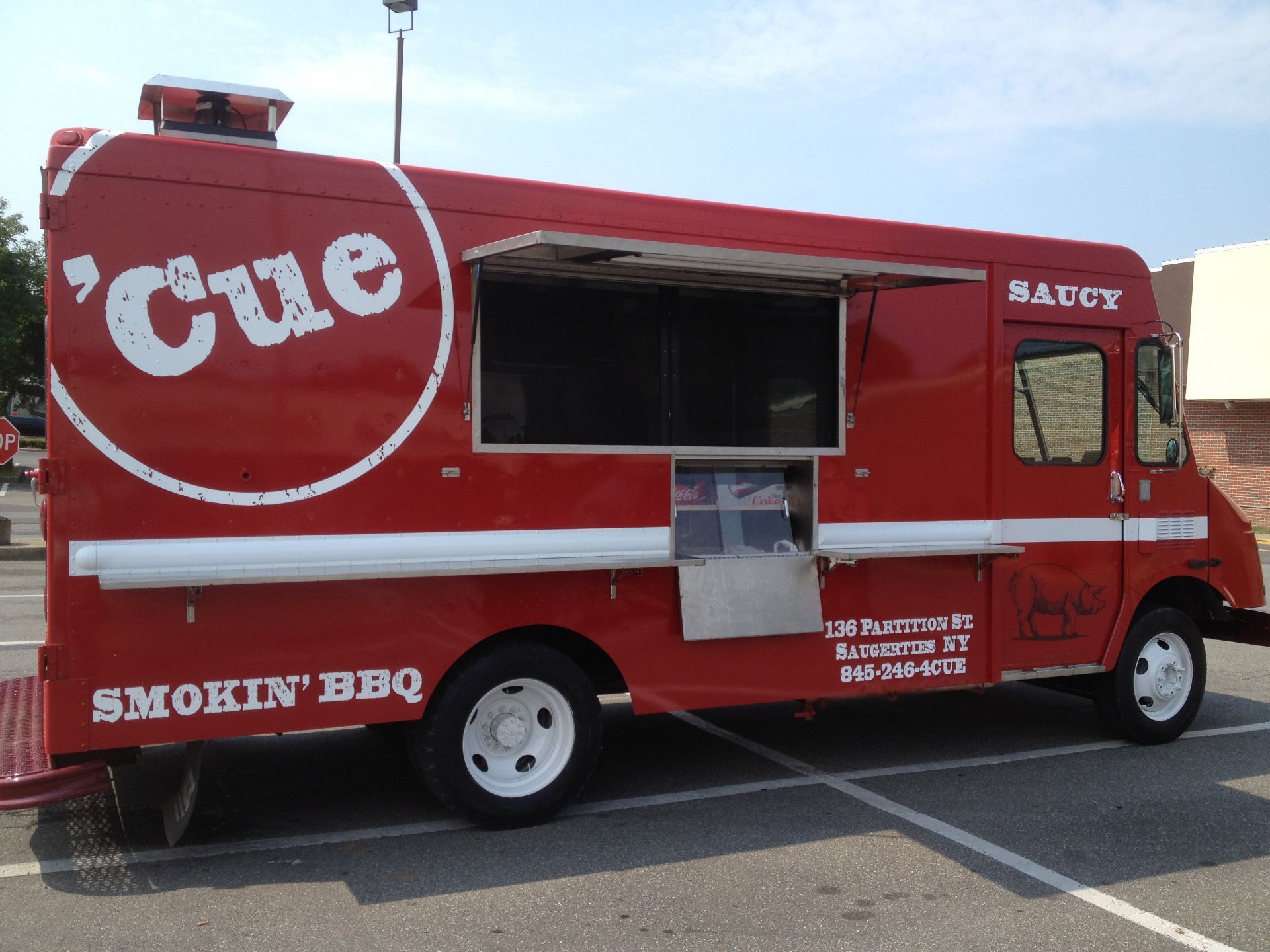 A red cue food truck is parked in a parking lot