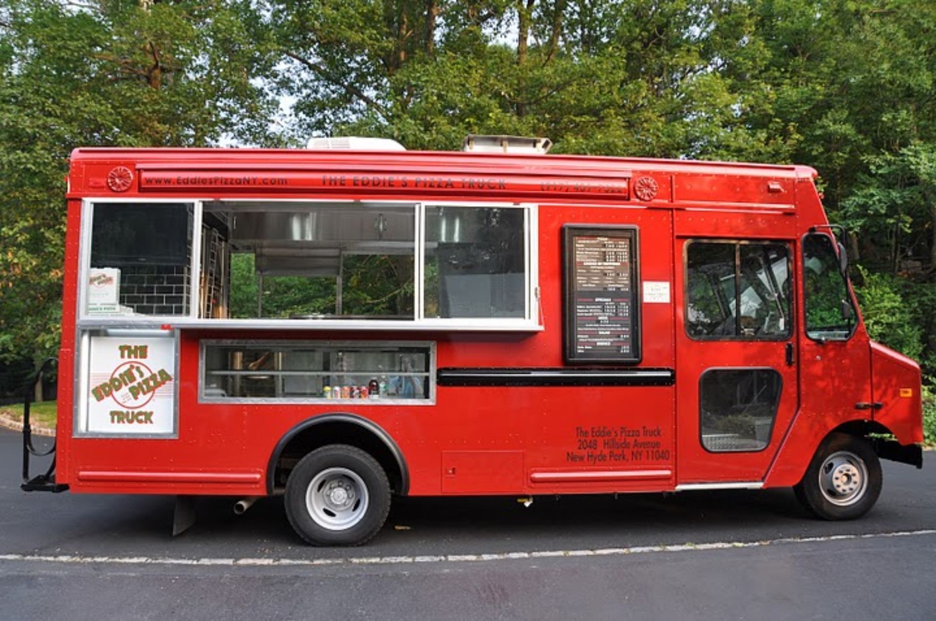 A red food truck is parked on the side of the road