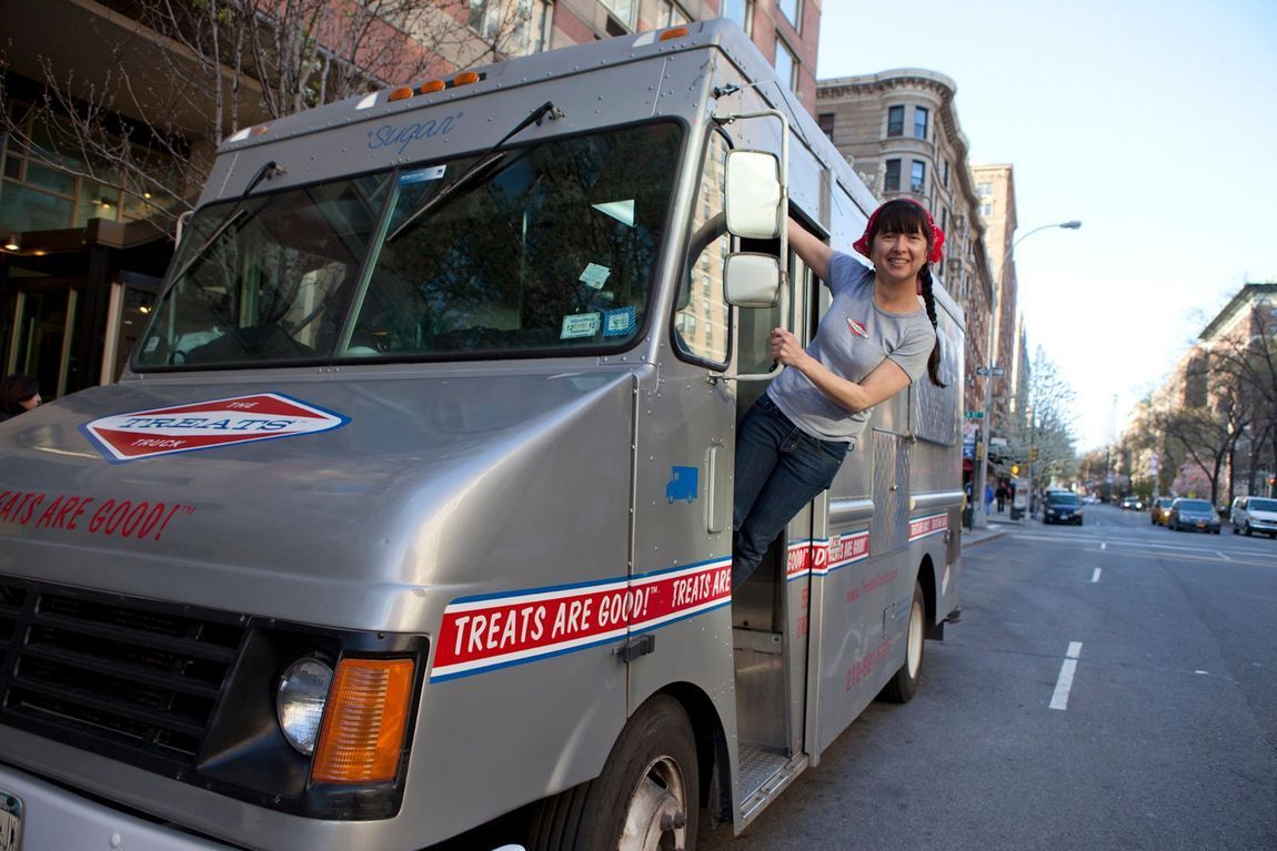 A man is getting out of a food truck on a city street.