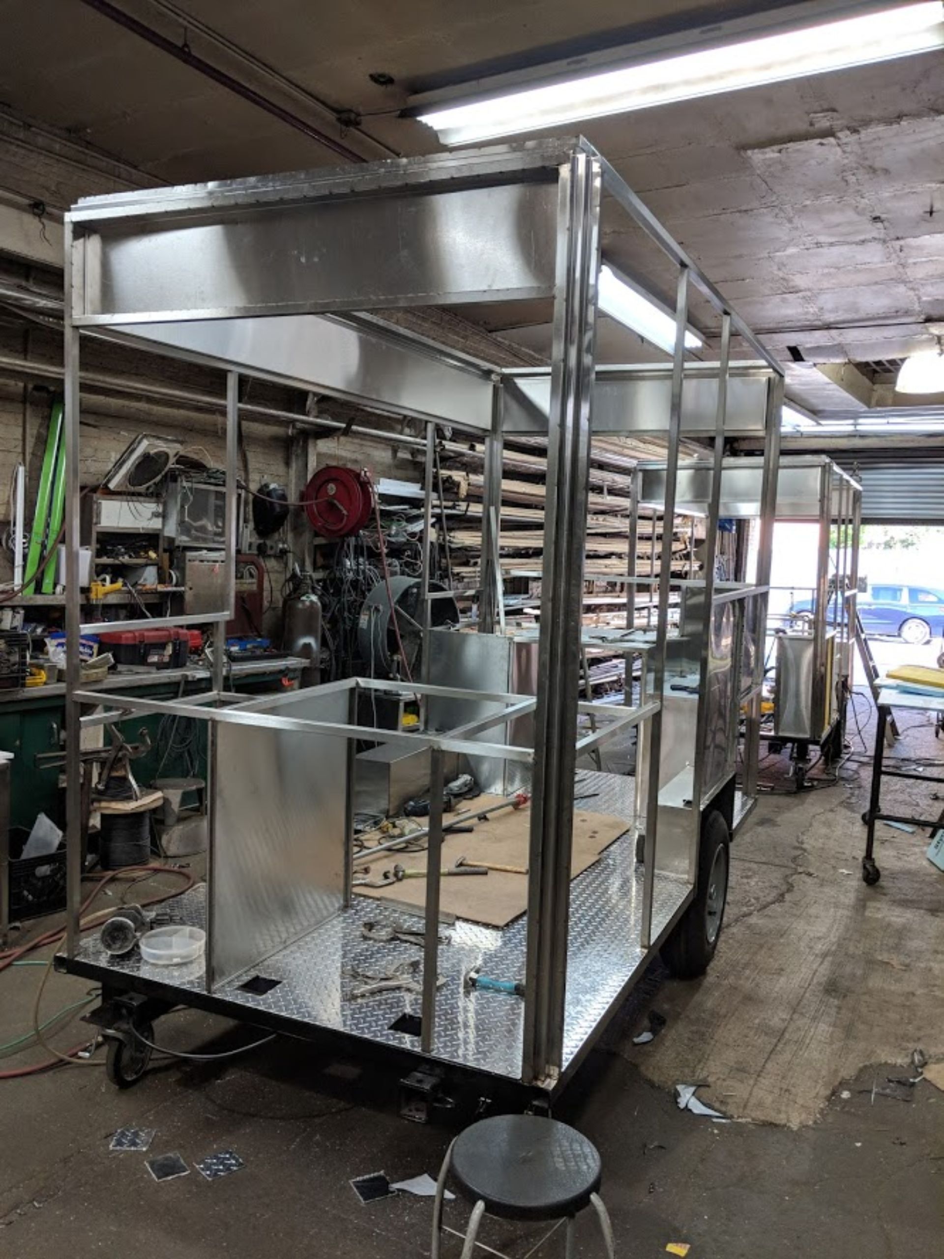 A stainless steel trailer is being built in a garage.