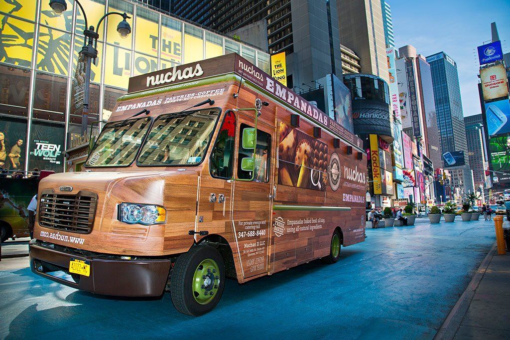 A food truck is driving down a city street.