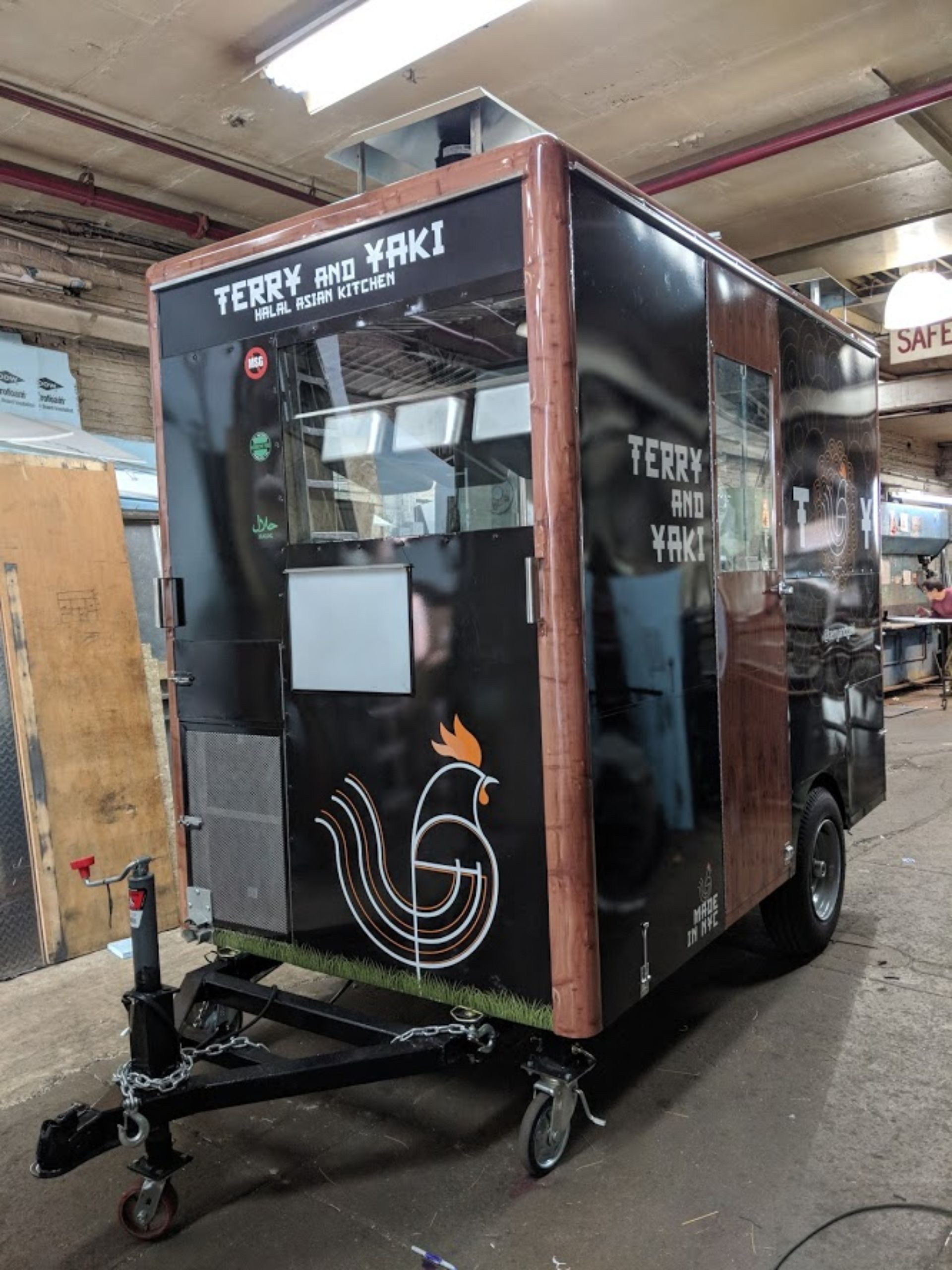 A food truck is sitting on a trailer in a garage.