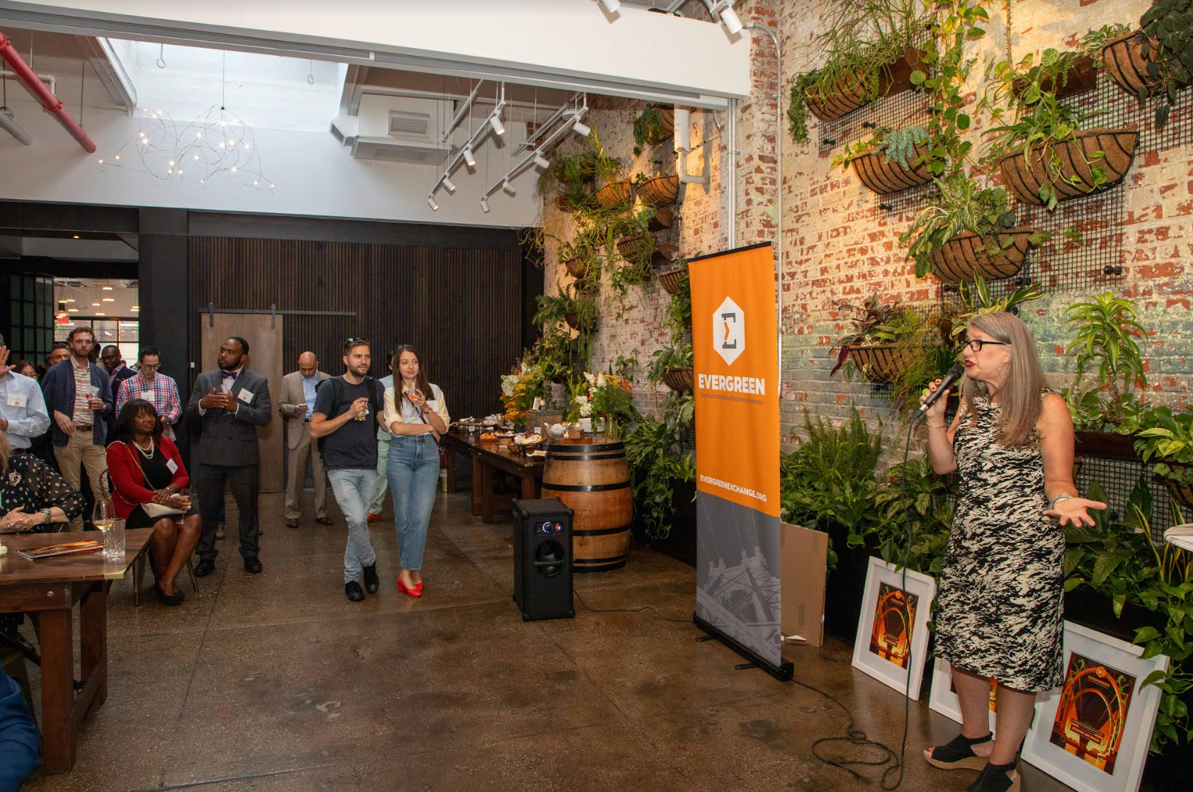 A woman is standing in front of a microphone in a room with people.