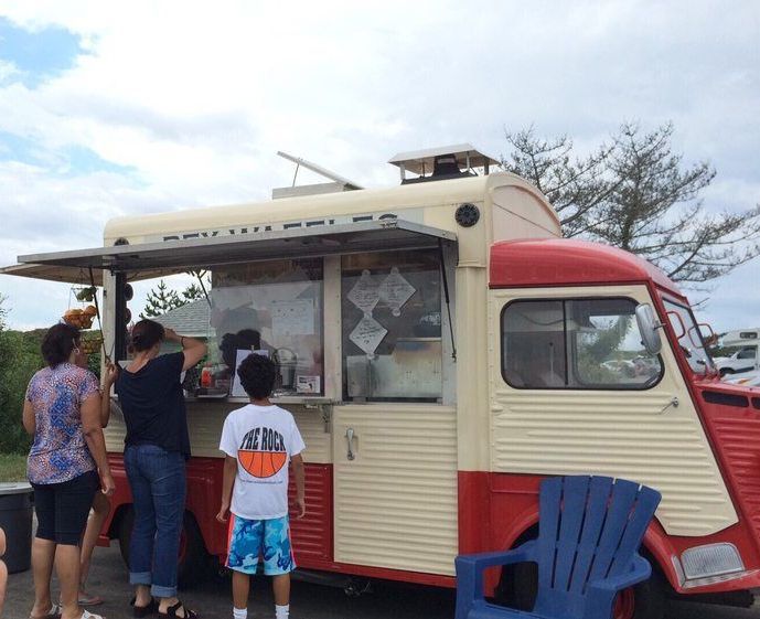 A group of people standing in front of a food truck