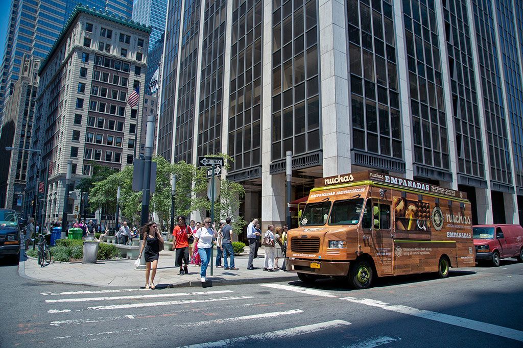 A food truck is parked on the side of the road in front of a building.