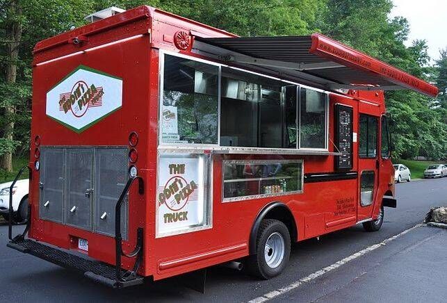 A red food truck is parked in a parking lot.