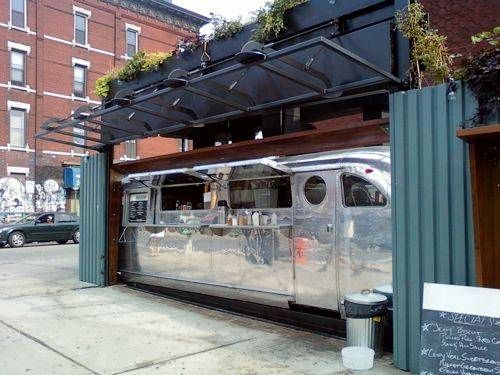 A food truck is parked in front of a building on the side of the road.