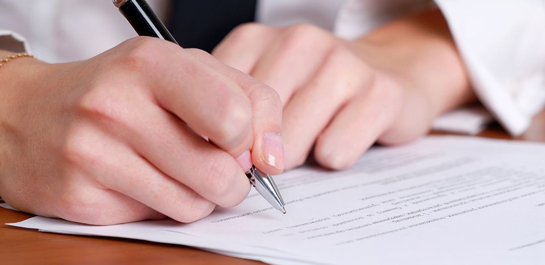 A person is writing on a piece of paper with a pen.