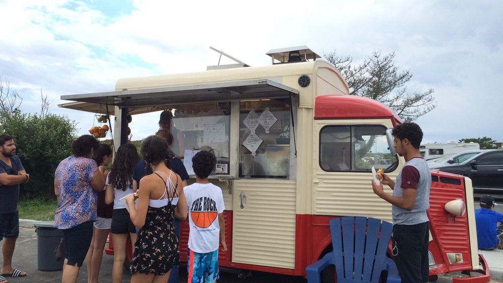 A group of people are standing in front of a food truck.