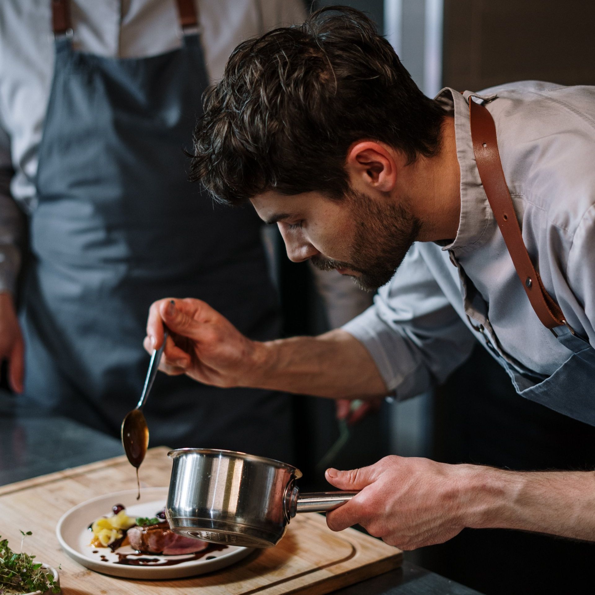 A man is pouring sauce on a plate of food