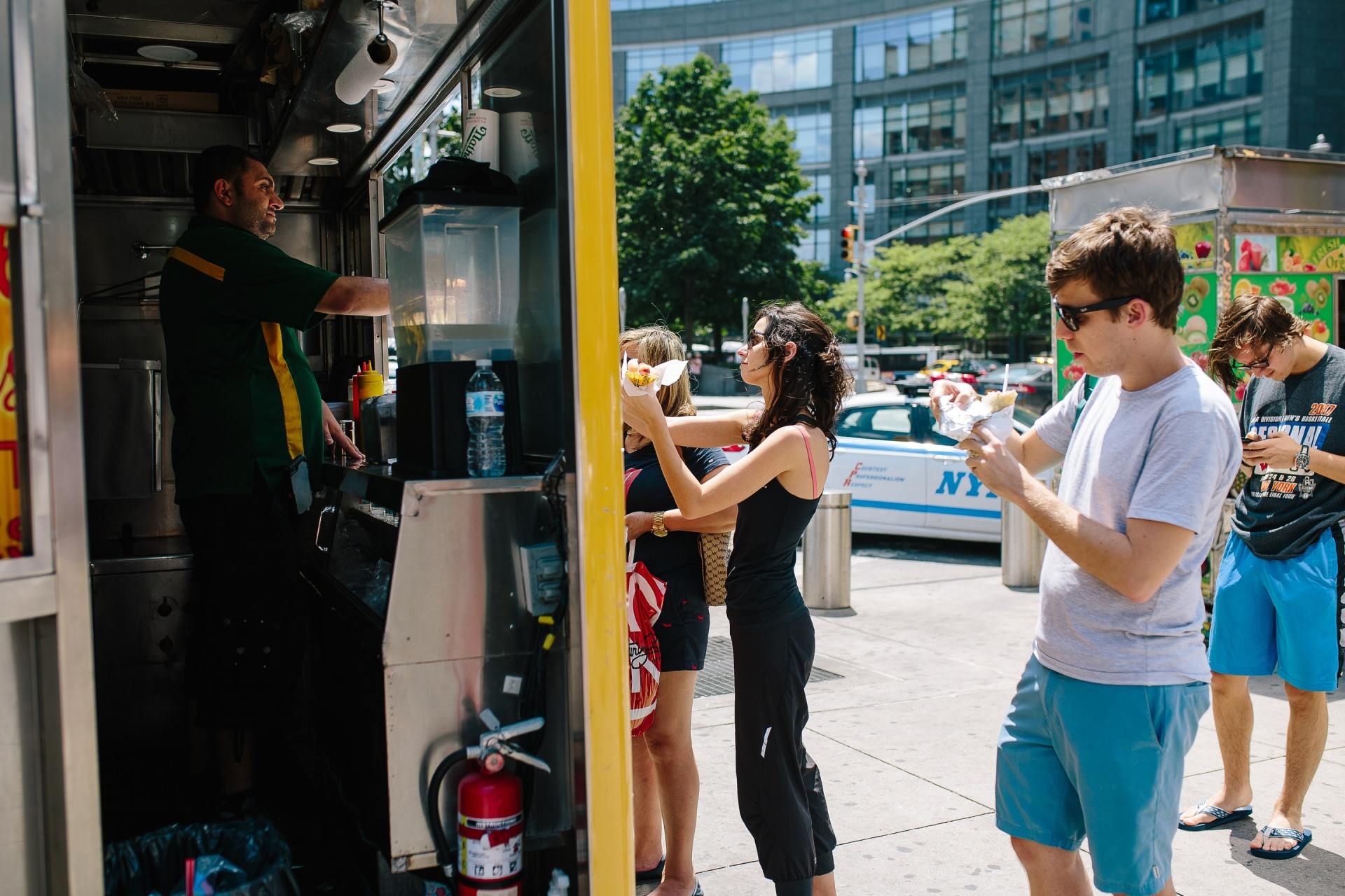 A group of people are standing outside of a food truck.