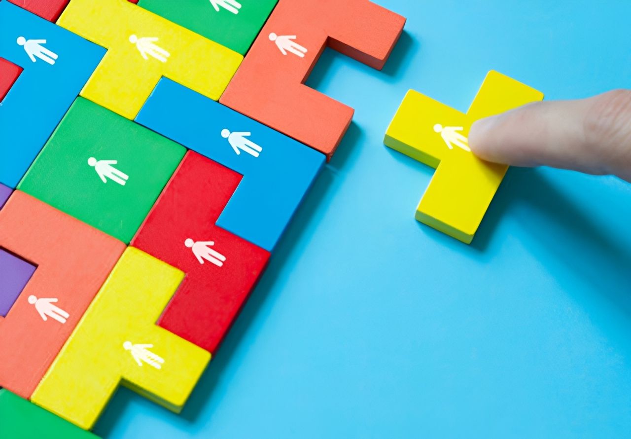 Colorful interlocking puzzle pieces on blue background, with a finger touching a yellow piece