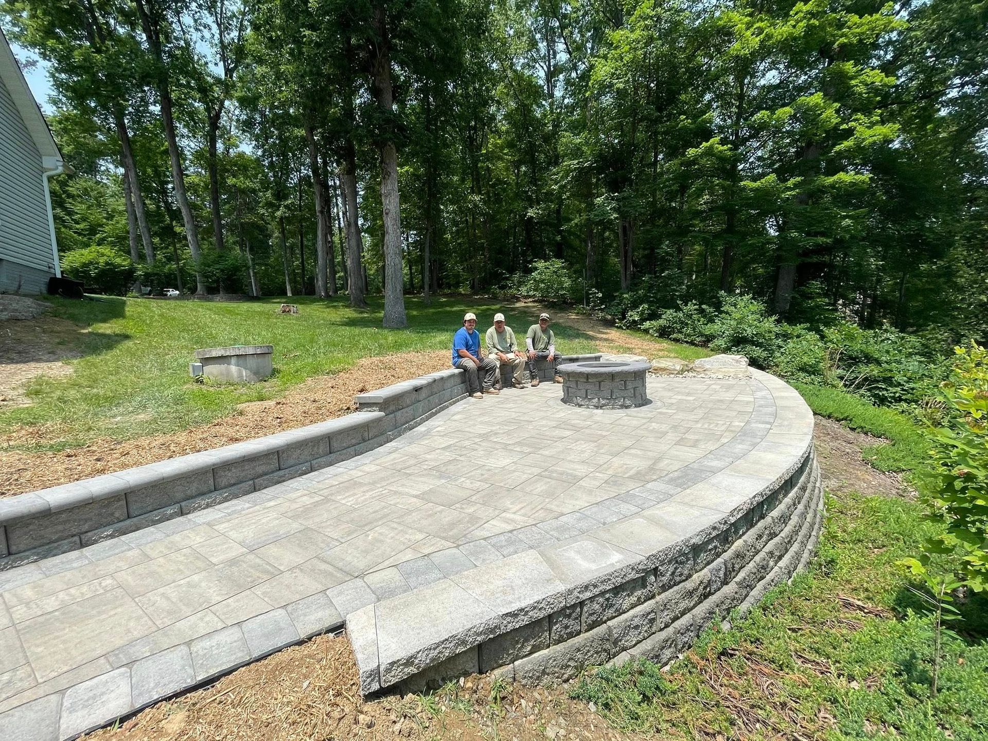 Curved stone patio with children sitting near the top in a leafy backyard garden