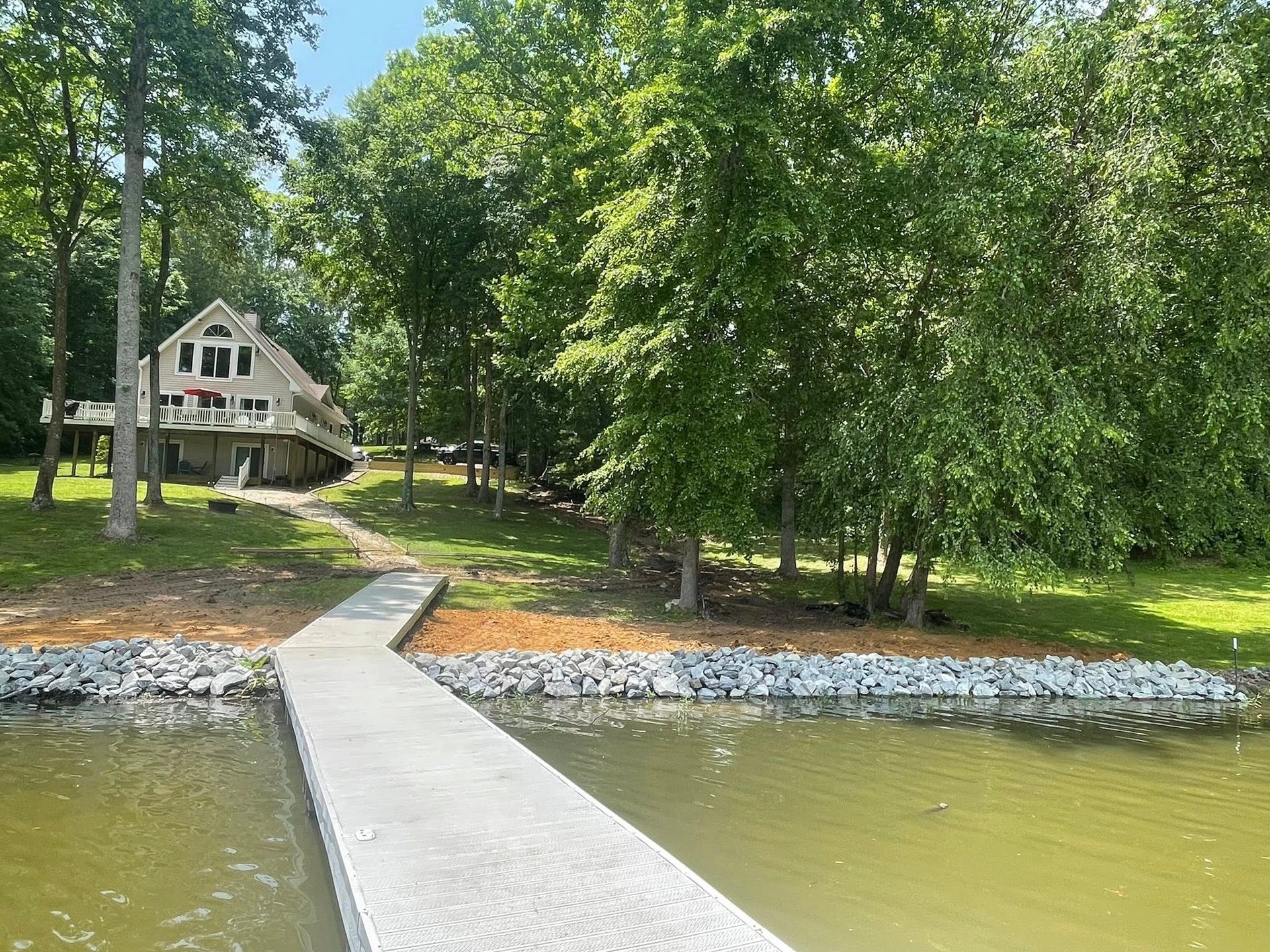 Wooden dock leading to a lakeside cabin surrounded by green trees