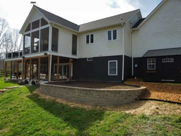 Two-story house with white siding, black lower level, and a raised porch on a grassy lot