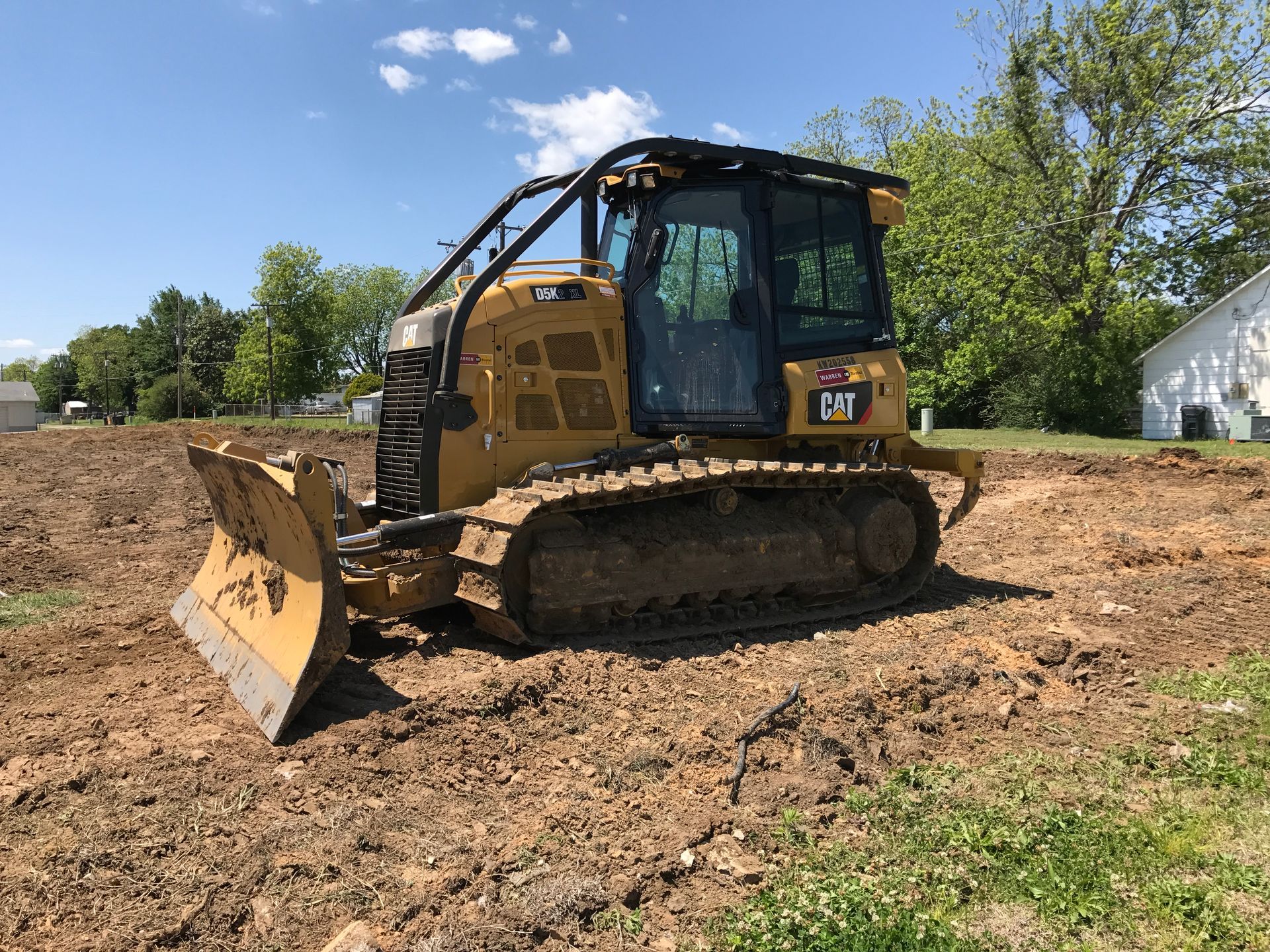 Yellow bulldozer on muddy ground, preparing a construction site under a blue sky.