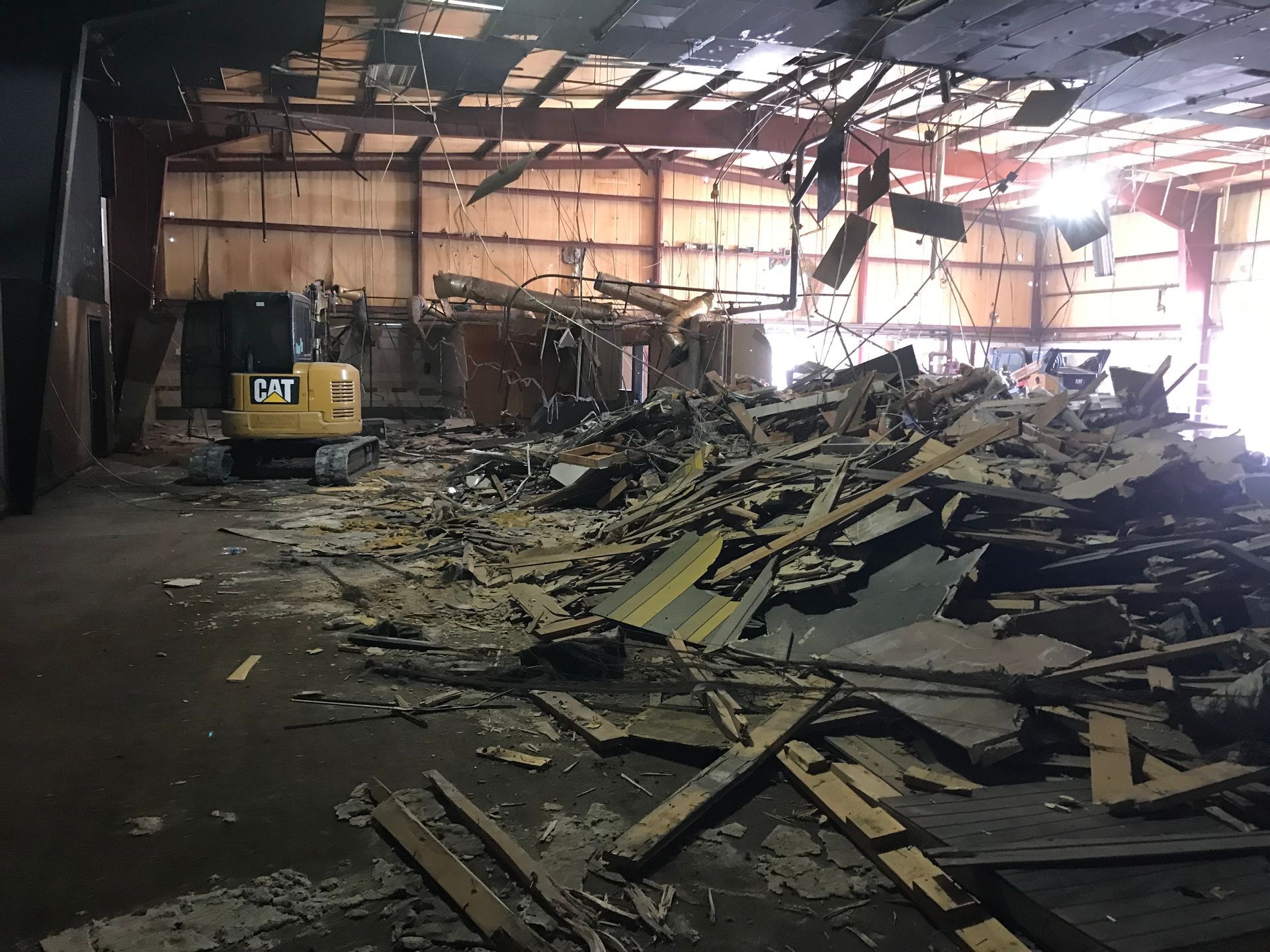 Demolition site with rubble pile and yellow excavator inside building.