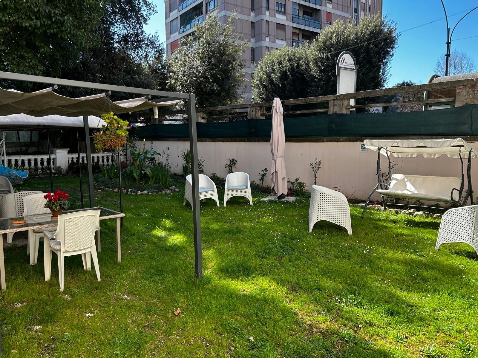 Un prato con tavolo, sedie e un'altalena.