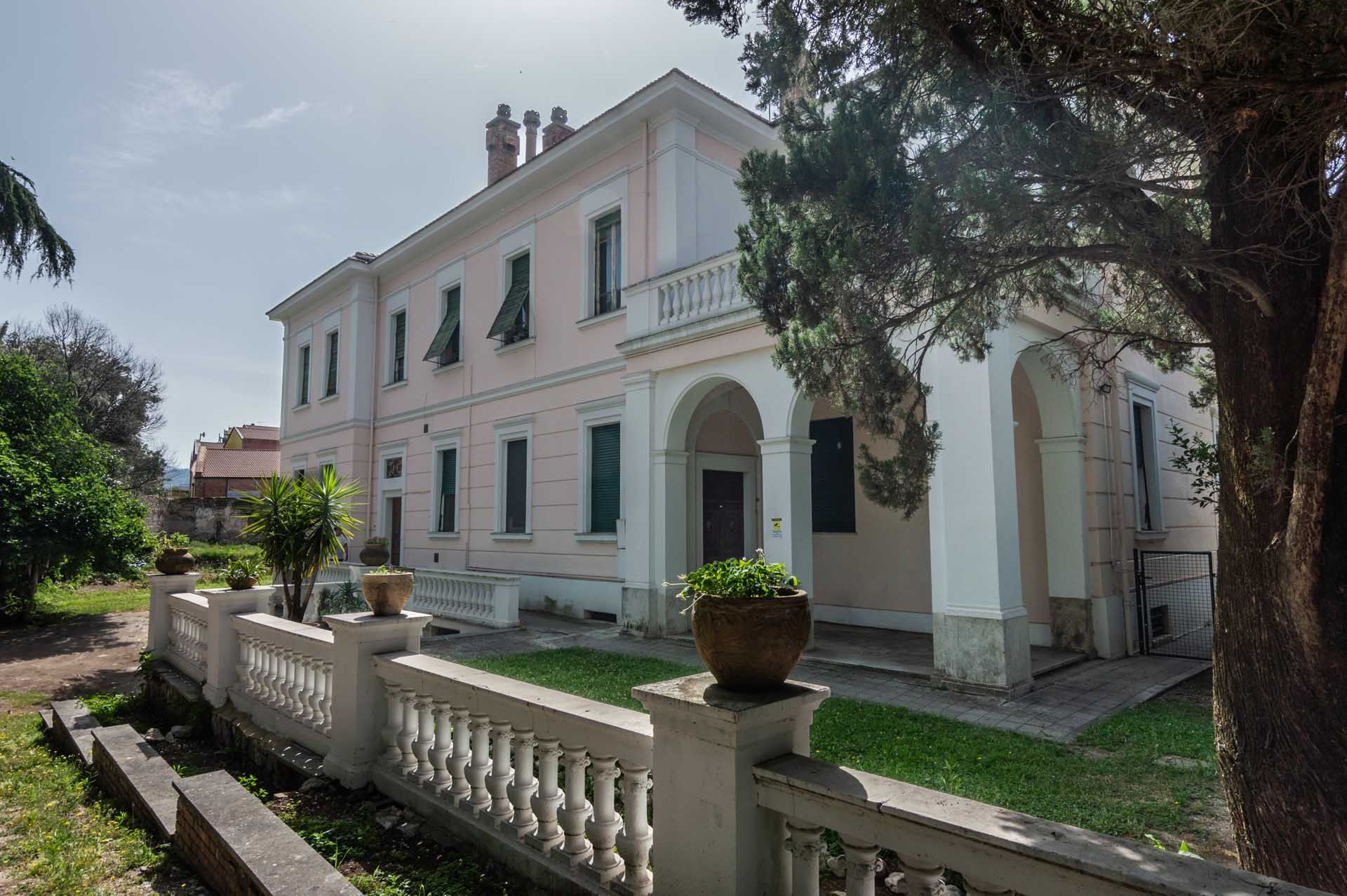 Una grande casa bianca con una recinzione davanti