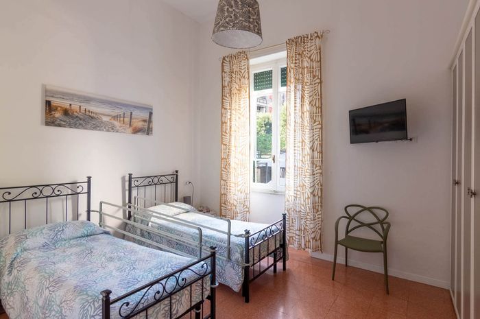 Una camera da letto con due letti, una sedia e una televisione.