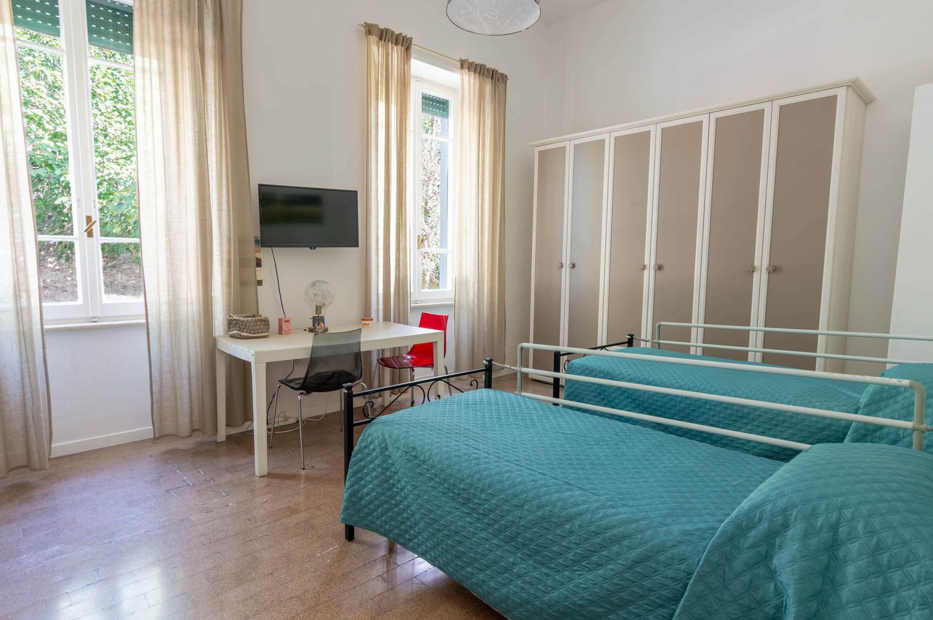Una camera da letto con due letti, una scrivania e una televisione.