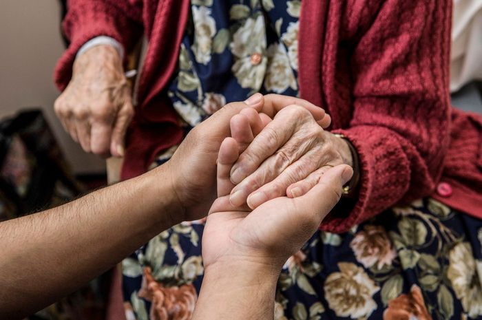 Una persona tiene la mano di una donna anziana.