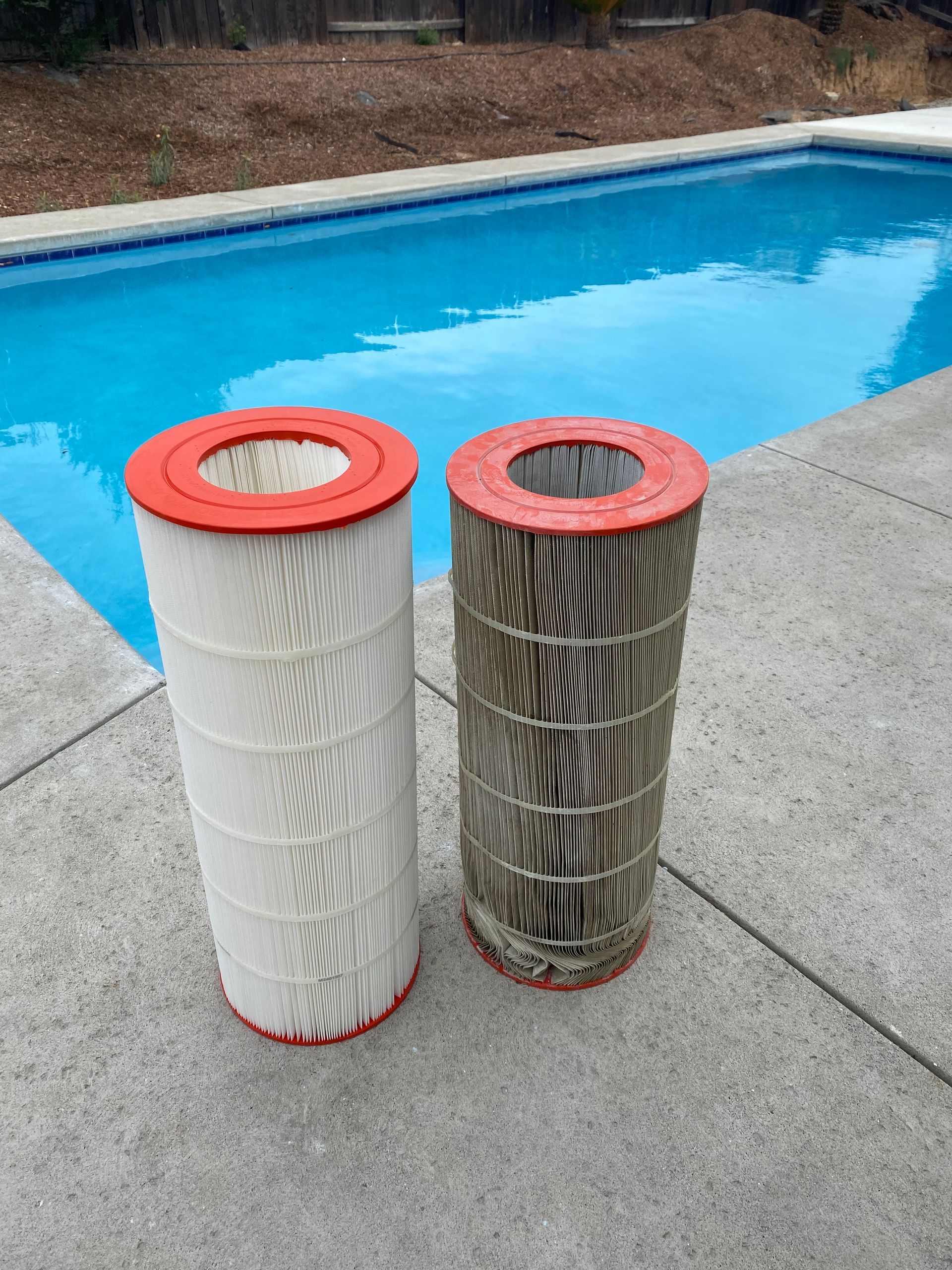 Two filters are sitting next to each other on the side of a pool.